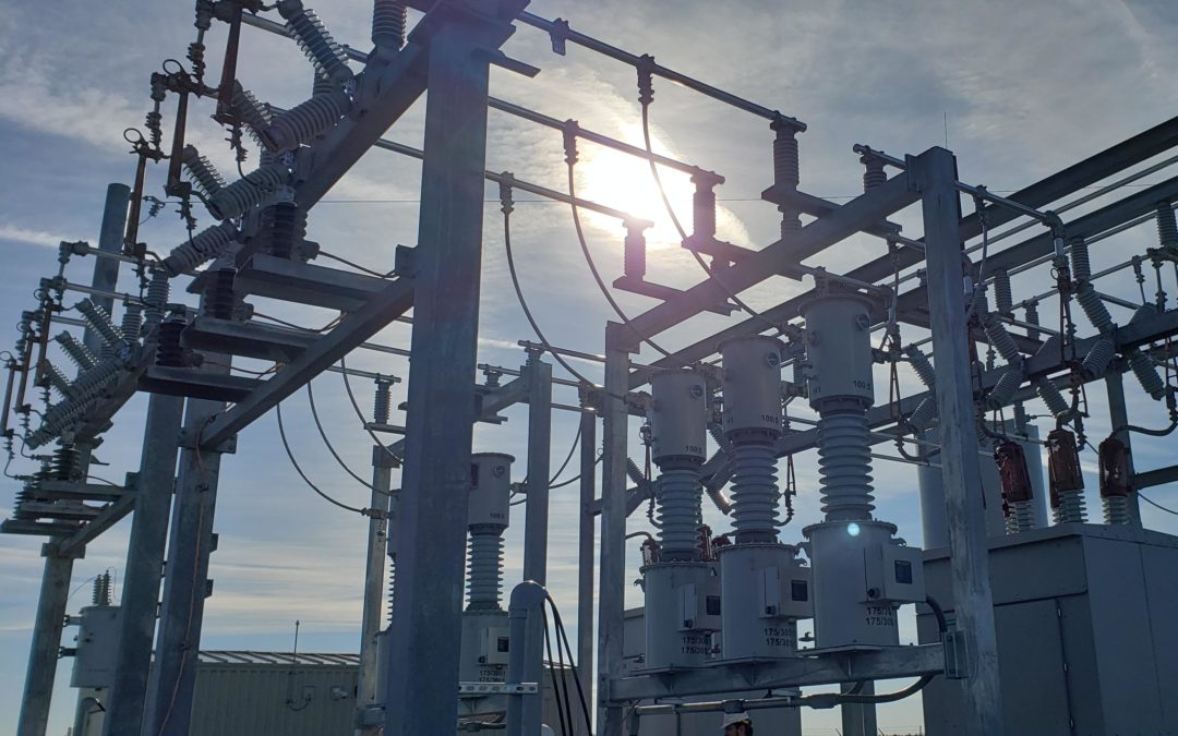 Substation with blue sky and sun behind